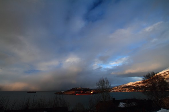 Evening sun shines on the city Narvik - in between the snow showers